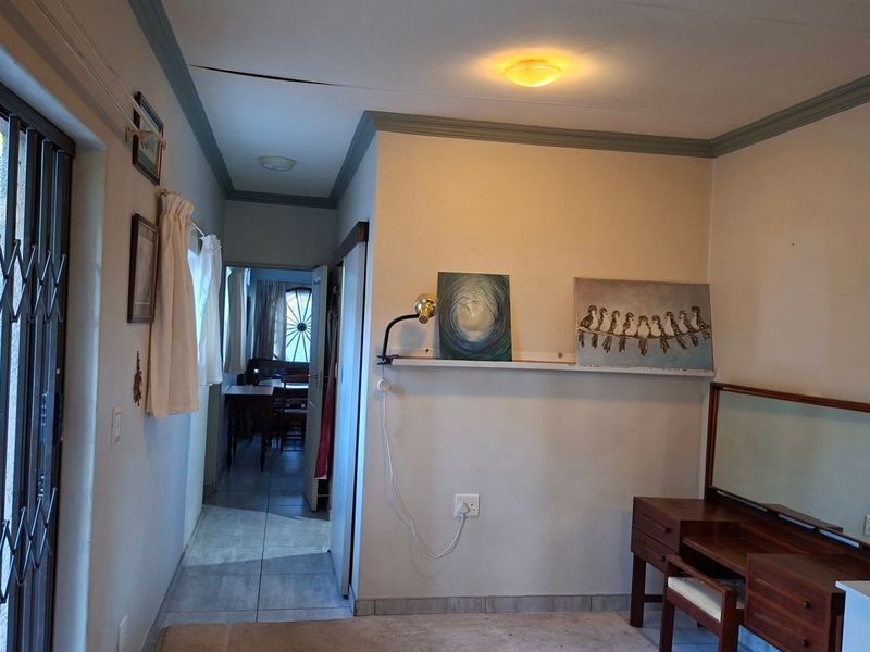 A living area featuring tiled flooring, ceiling cornicing, and a security gate, with a visible crack in the ceiling requiring attention.