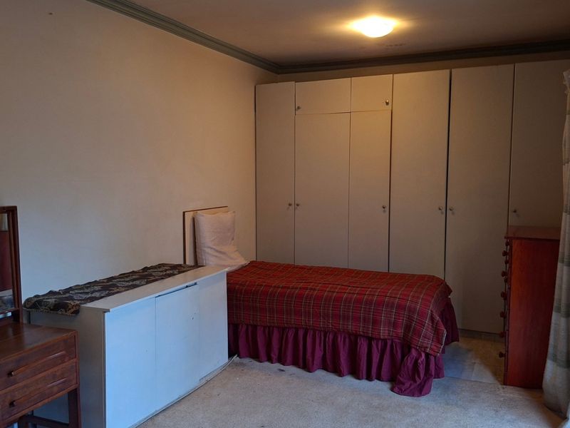 A bedroom featuring built-in cupboards and a sliding security gate, providing functional storage and access to the exterior.
