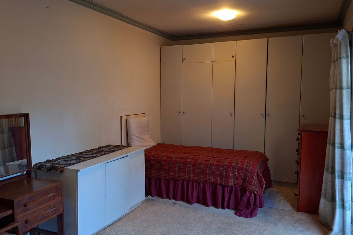 A bedroom featuring built-in cupboards and a sliding security gate, providing functional storage and access to the exterior.