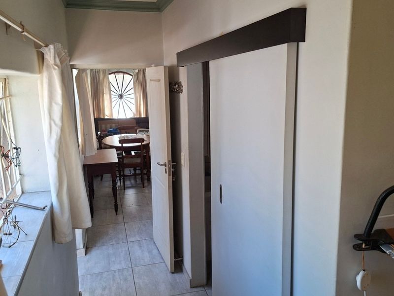 A functional hallway featuring tiled flooring, a sliding door, and a window with security bars, providing access to adjacent living spaces.