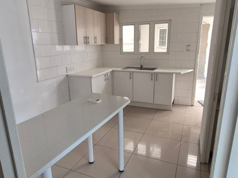 A clean, modern kitchen featuring white cabinetry, subway tile backsplash, tiled flooring, and a functional breakfast counter area.