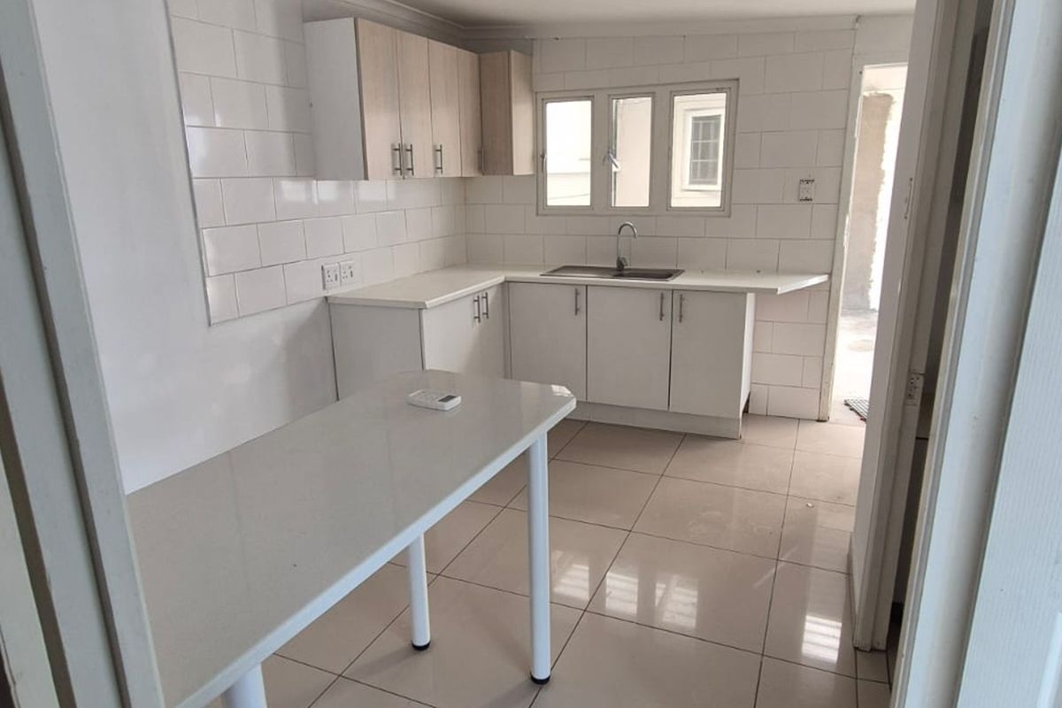 A clean, modern kitchen featuring white cabinetry, subway tile backsplash, tiled flooring, and a functional breakfast counter area.