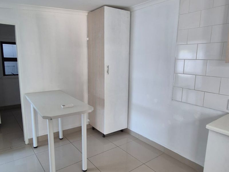 A functional kitchen area featuring tiled flooring, a tiled backsplash, and built-in cabinetry, offering a clean and neutral space ready for customization.