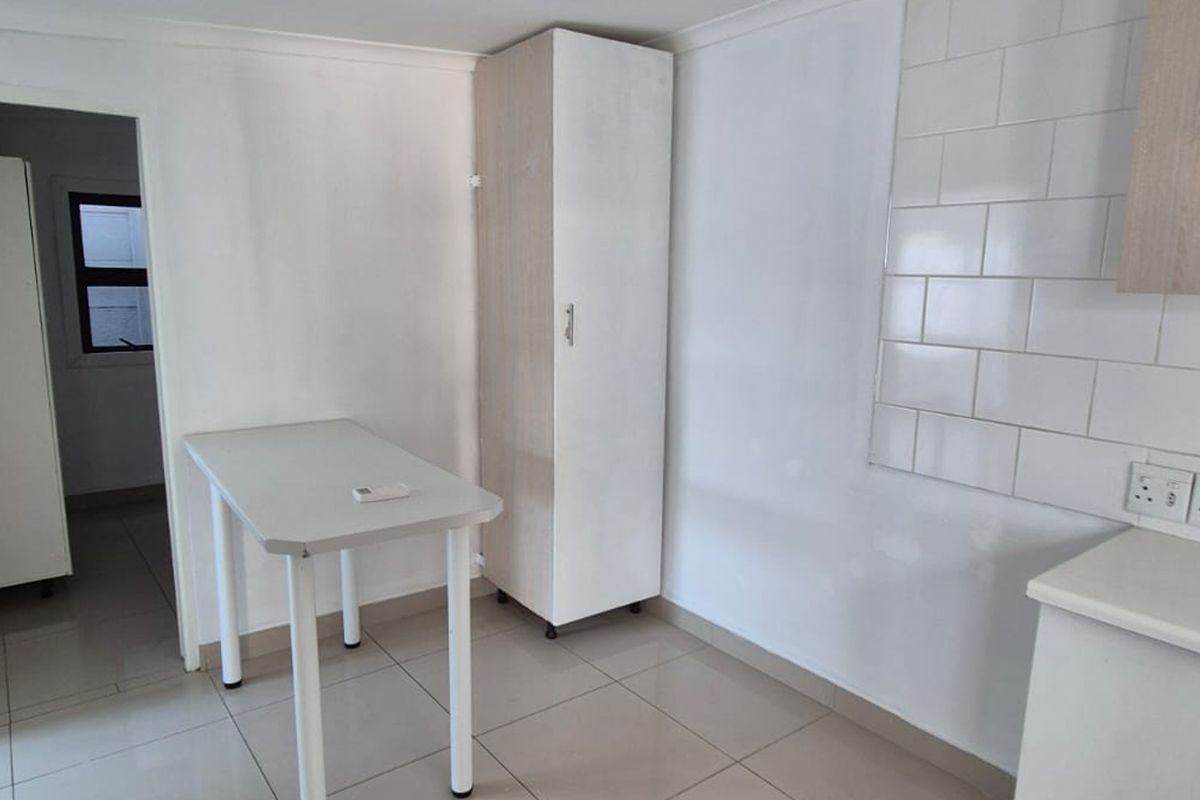 A functional kitchen area featuring tiled flooring, a tiled backsplash, and built-in cabinetry, offering a clean and neutral space ready for customization.