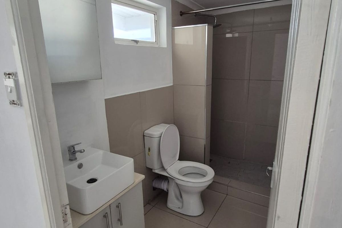 A clean, functional bathroom featuring a modern vanity, toilet, and a tiled shower enclosure with neutral finishes.