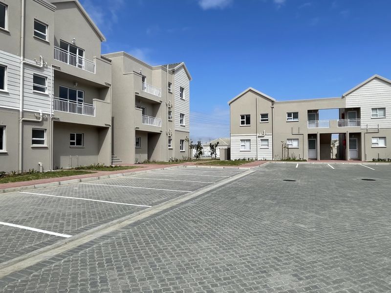 Exterior view of a modern apartment complex featuring paved parking bays and multi-story residential buildings with balconies.