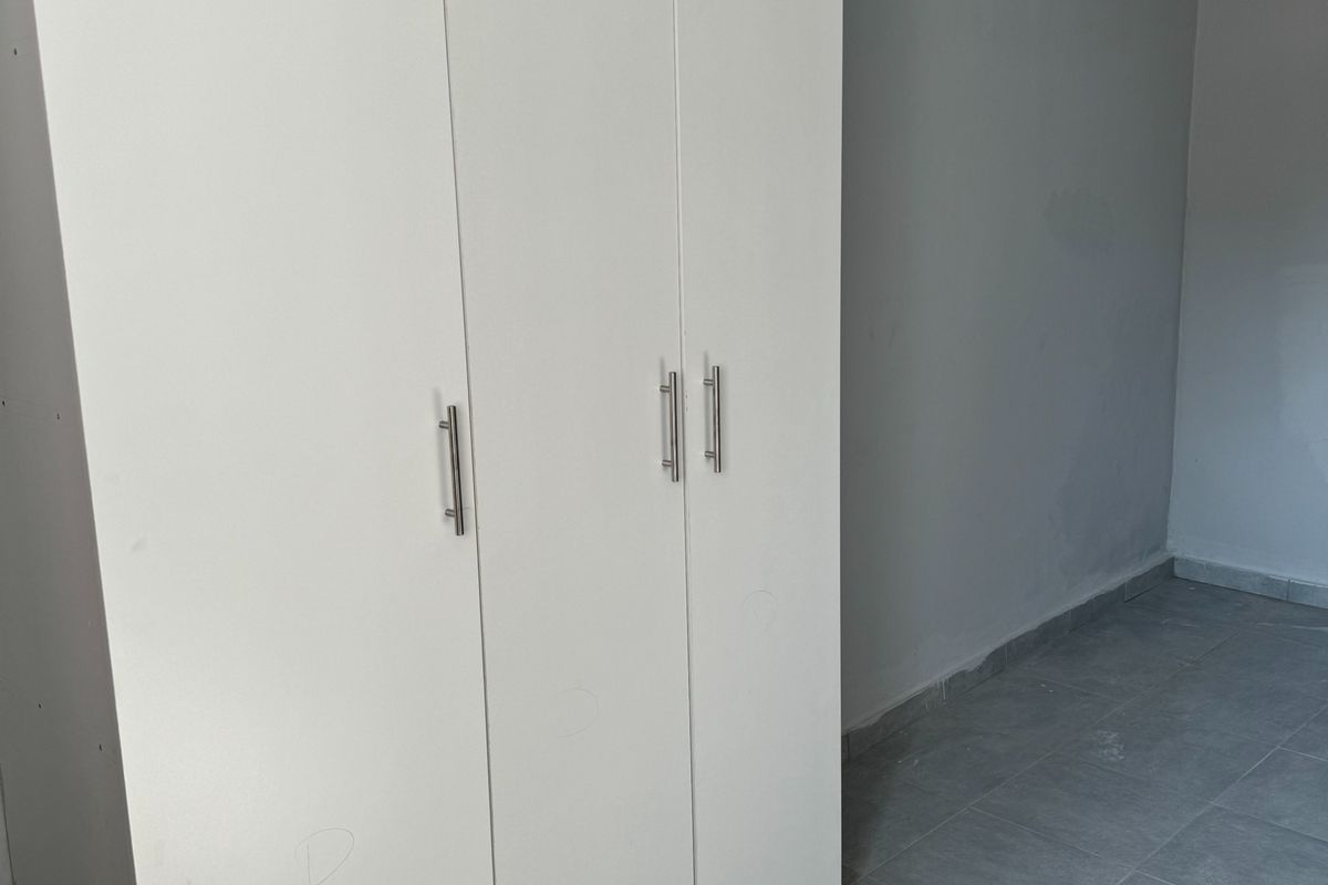 A bedroom featuring built-in white cabinetry, grey tiled flooring, and neutral wall finishes.
