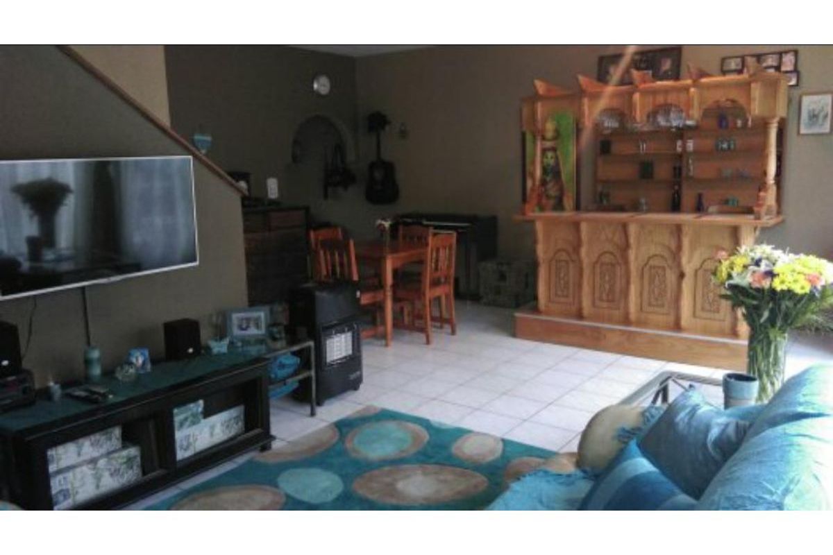 A living room area featuring tiled flooring, a built-in wooden bar, and an adjacent staircase.