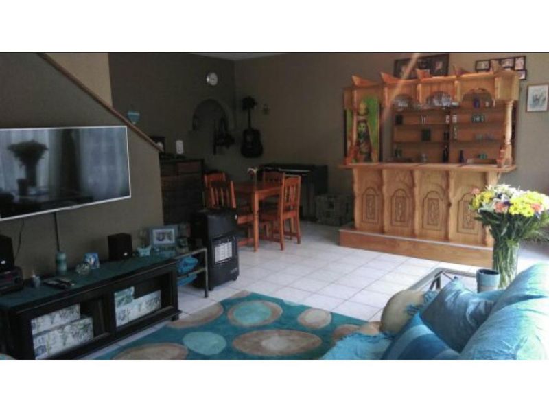A living room area featuring tiled flooring, a built-in wooden bar, and an adjacent staircase.