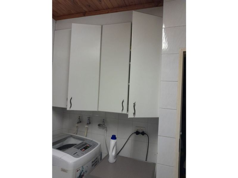 Laundry area featuring wall-mounted cabinetry, tiled splashback, and timber ceiling, requiring minor repairs to cabinet alignment.