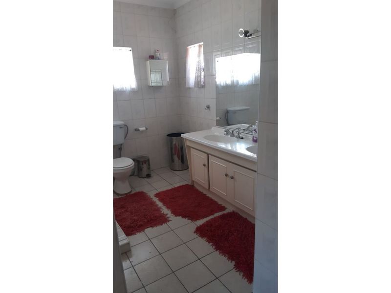 A functional bathroom featuring a double vanity cabinet, tiled walls and floors, and a wall-mounted mirror.