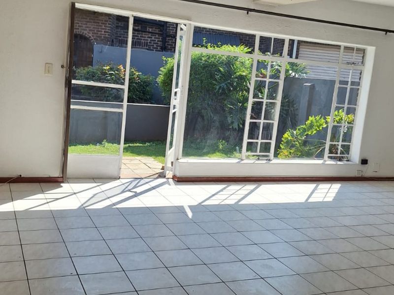 Spacious living area featuring neutral tiled flooring and large glass sliding doors providing direct access to the rear garden.