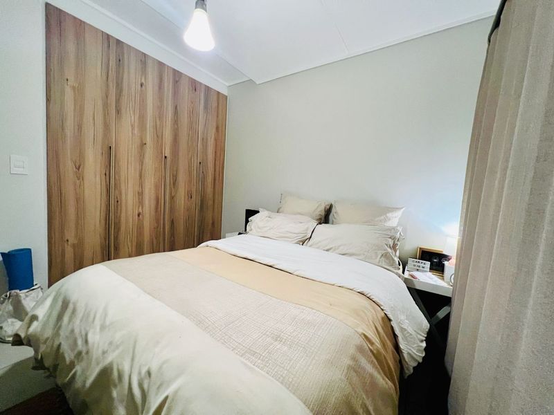 A cozy bedroom featuring floor-to-ceiling built-in wooden cupboards, providing ample storage space within a neutral-toned room.