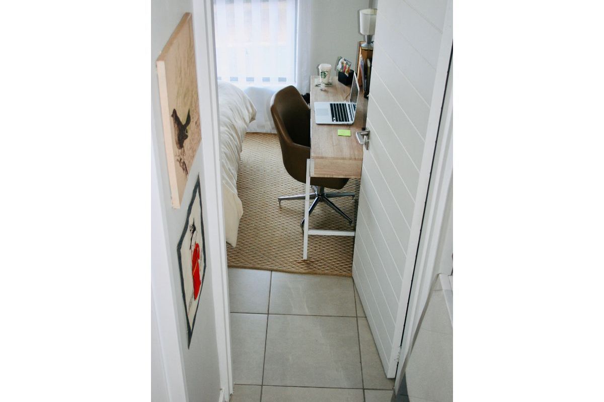 A view into a compact bedroom featuring tiled flooring and a modern horizontal panel door.
