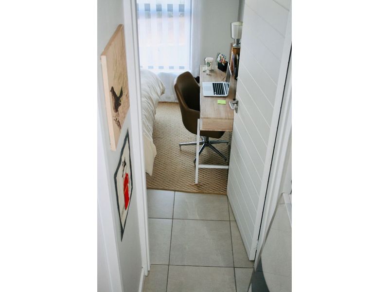 A view into a compact bedroom featuring tiled flooring and a modern horizontal panel door.