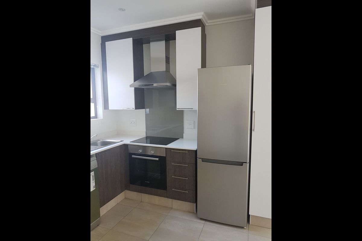 Modern kitchen featuring two-tone cabinetry, stone countertops, integrated stainless steel appliances, and tiled flooring.
