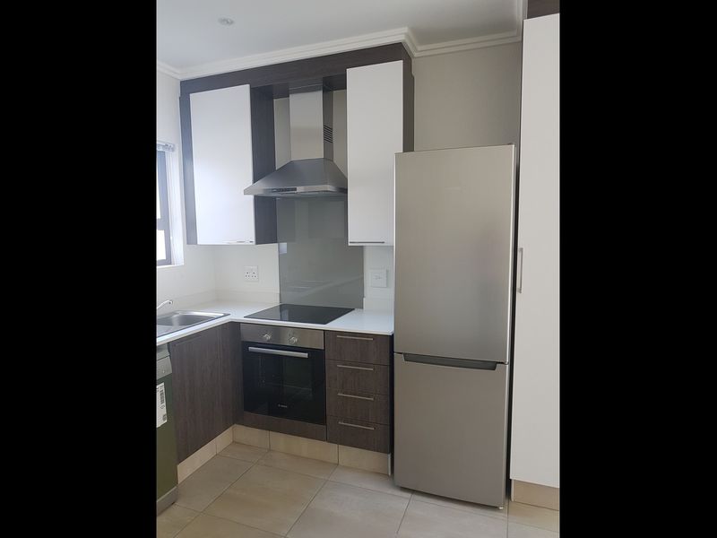 Modern kitchen featuring two-tone cabinetry, stone countertops, integrated stainless steel appliances, and tiled flooring.