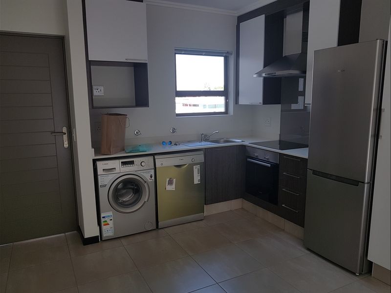 Modern kitchen featuring built-in cabinetry, integrated appliances, stainless steel sink, and tiled flooring in a functional layout.