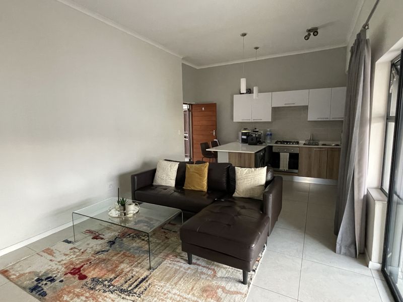 Open-plan living area featuring a modern kitchen with built-in cabinetry, gas hob, and under-counter oven, seamlessly flowing into the lounge space.