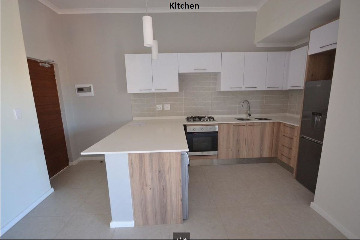 Modern kitchen featuring light wood-tone lower cabinets, white upper cabinetry, stone countertops, built-in oven, gas hob, and a functional breakfast bar peninsula.