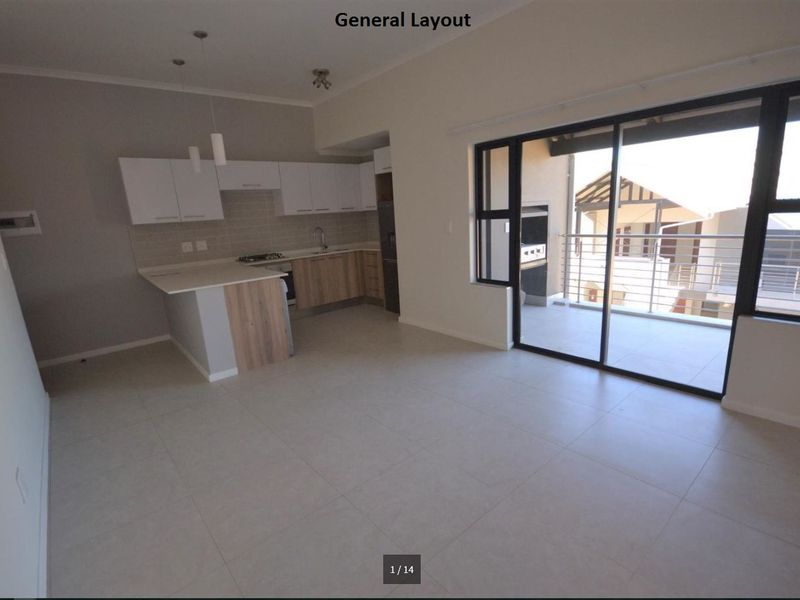 Modern open-plan kitchen and living area featuring tiled floors, sleek cabinetry, and large sliding doors leading to a private balcony.