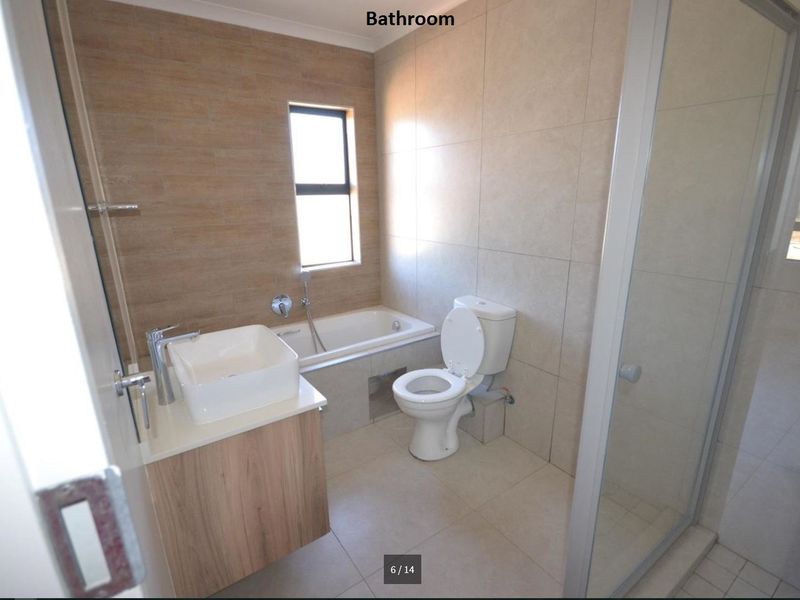 A modern bathroom featuring a built-in vanity with a vessel sink, a bathtub, a toilet, and a separate glass-enclosed shower with neutral tiling.
