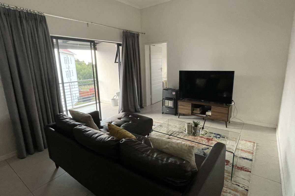 A bright living room featuring tiled flooring and a large sliding glass door providing access to an attached balcony.
