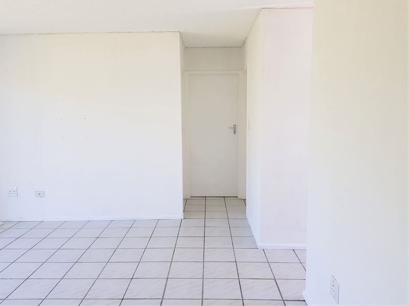 An empty, neutrally painted living area featuring white ceramic floor tiles and a clean, minimalist layout ready for personalization.