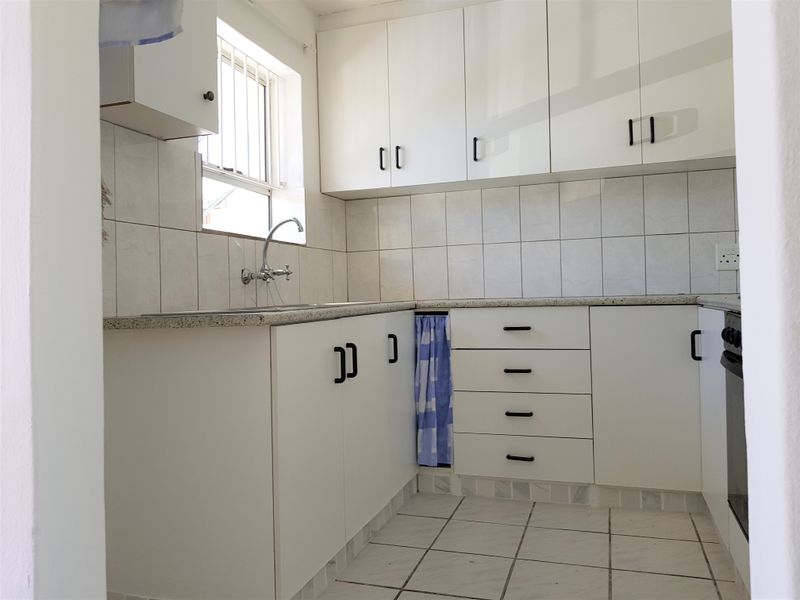 A functional kitchen featuring white built-in cabinetry, tiled backsplash, laminate countertops, and a built-in oven, offering a clean and practical workspace.