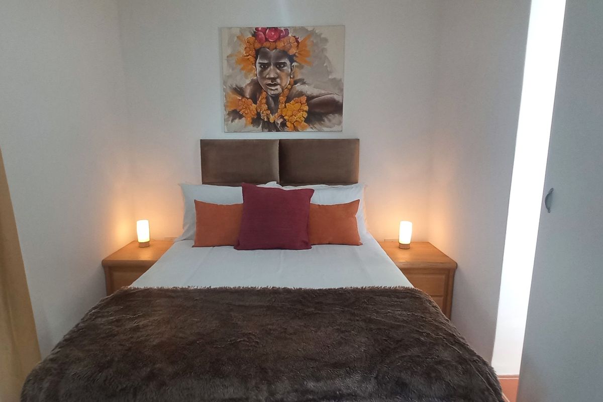 A cozy bedroom featuring a built-in headboard and a vertical light feature, creating a warm and inviting atmosphere.