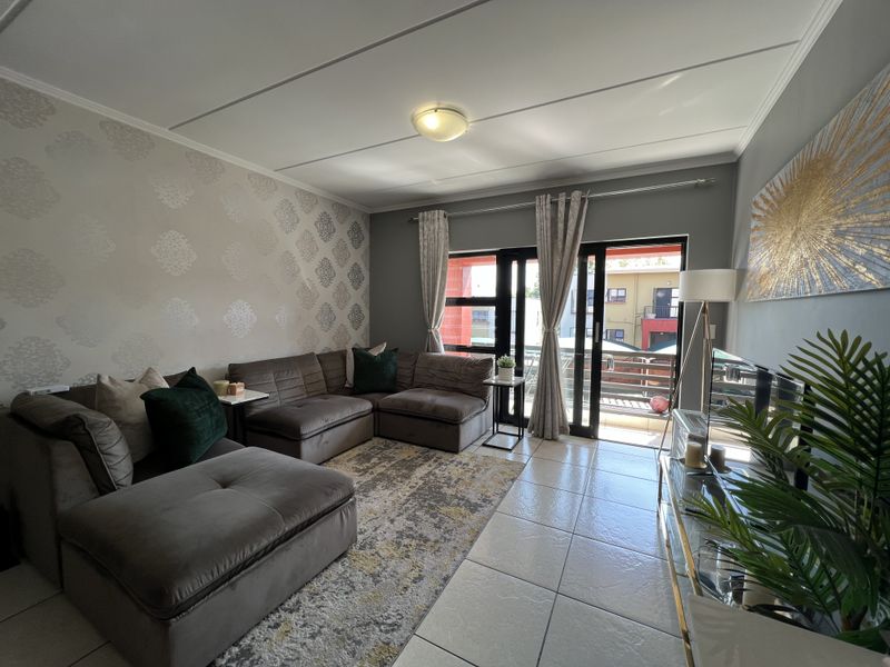 A well-maintained living room featuring tiled flooring and large sliding glass doors that provide access to an outdoor balcony area.