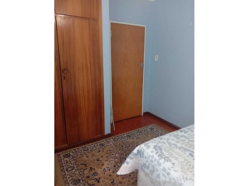 A bedroom featuring built-in wooden cabinetry, laminate flooring, and a standard interior door.