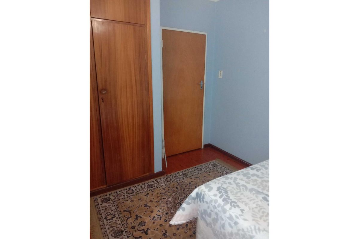 A bedroom featuring built-in wooden cabinetry, laminate flooring, and a standard interior door.