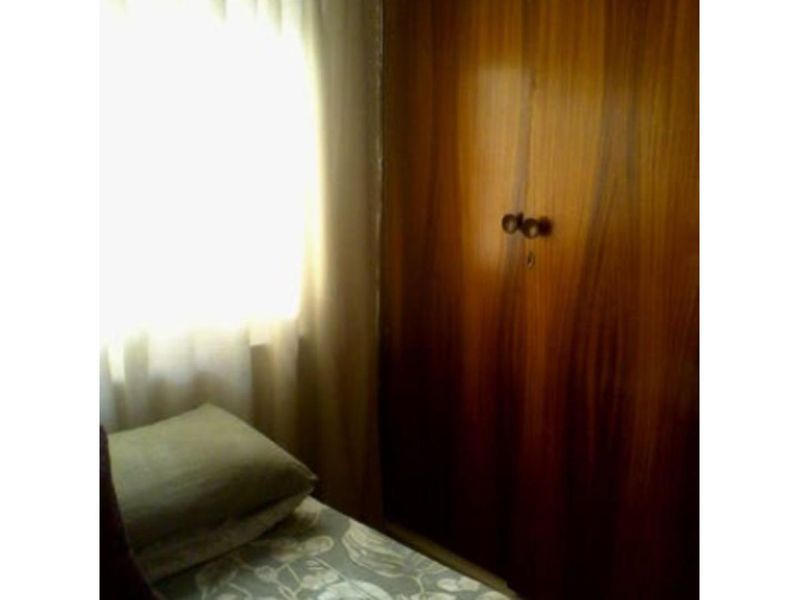 A bedroom featuring a built-in wooden wardrobe and natural light from the window.