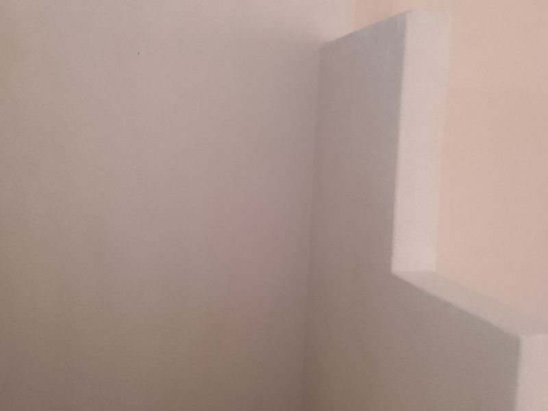 An empty interior space featuring tiled flooring and a partial partition wall, suitable for various living configurations.