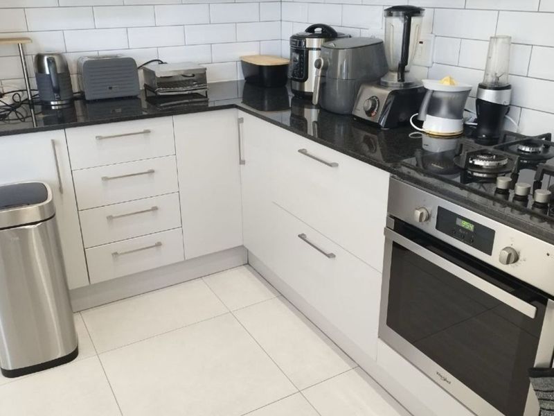 A modern kitchen featuring white cabinetry, granite countertops, a subway tile backsplash, and integrated stainless steel cooking appliances.