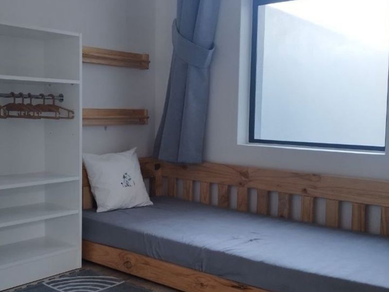 A functional bedroom featuring built-in shelving and a window, providing a clean and simple living space.