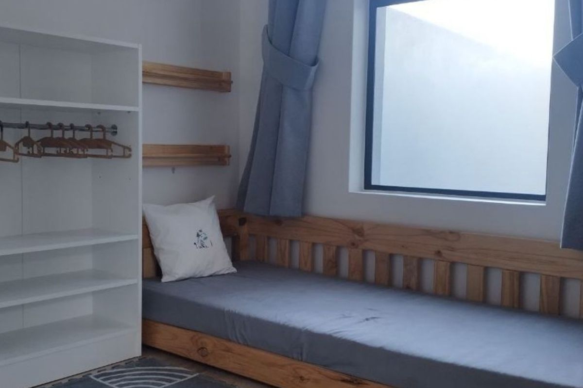 A functional bedroom featuring built-in shelving and a window, providing a clean and simple living space.