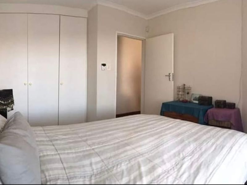 A functional bedroom featuring built-in cupboards, tiled flooring, and decorative coving, providing a neutral foundation for personal styling.