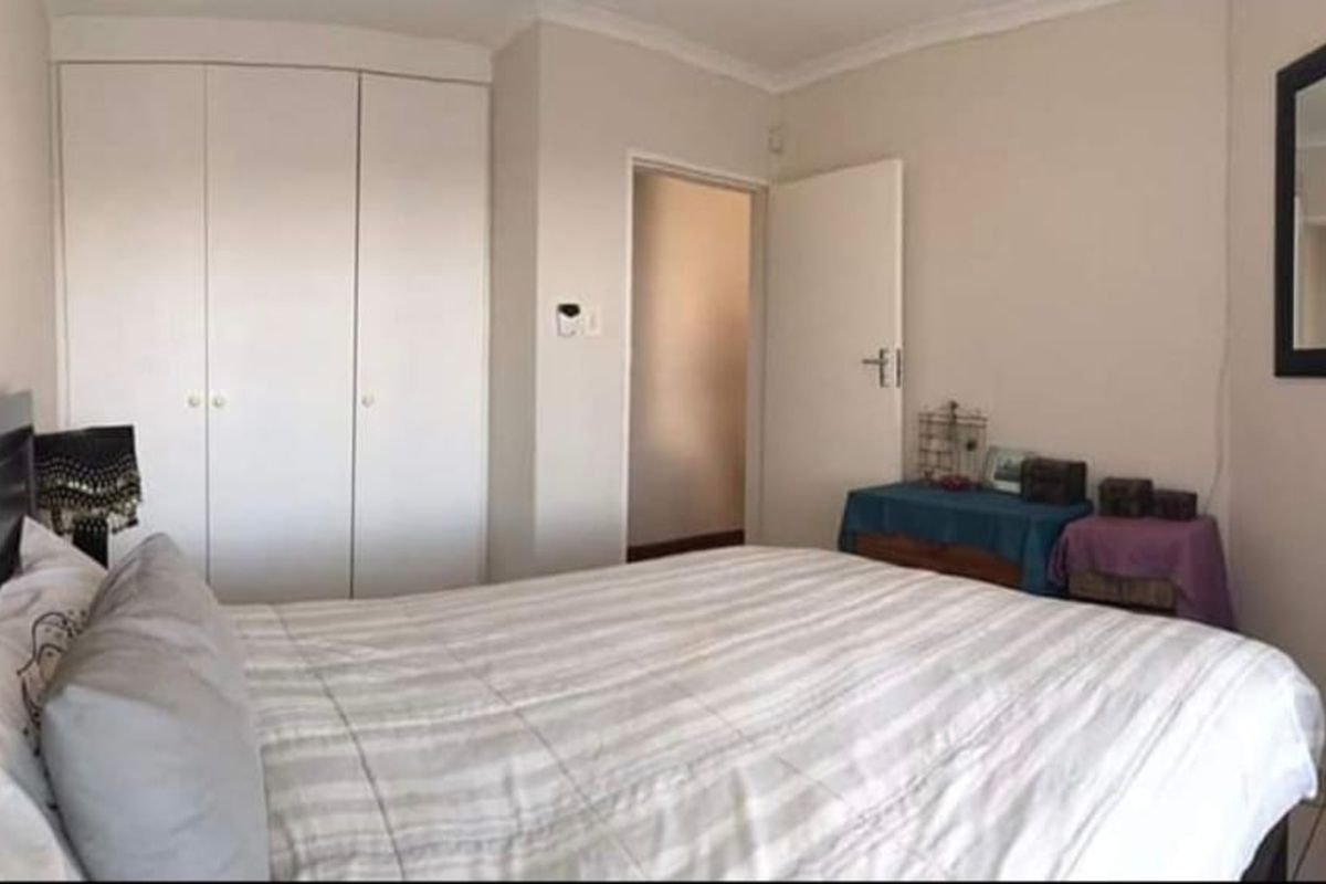 A functional bedroom featuring built-in cupboards, tiled flooring, and decorative coving, providing a neutral foundation for personal styling.