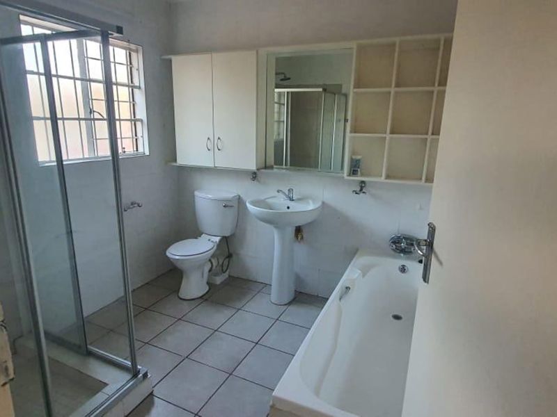 A functional bathroom featuring a pedestal basin, toilet, bathtub, and separate shower enclosure with tiled flooring and built-in storage cabinetry.