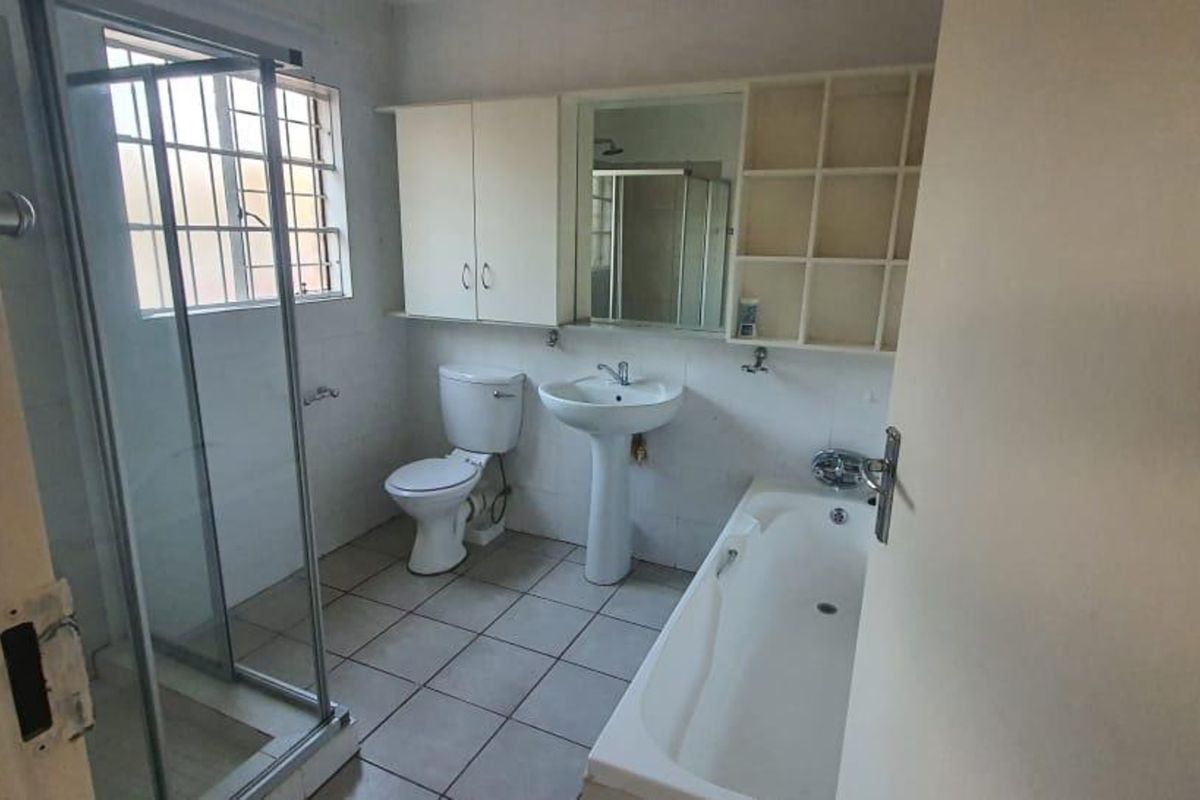 A functional bathroom featuring a pedestal basin, toilet, bathtub, and separate shower enclosure with tiled flooring and built-in storage cabinetry.