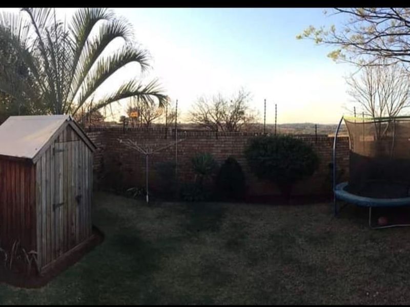 A private rear garden featuring a brick boundary wall with electric fencing, a wooden storage shed, and a rotary clothesline.