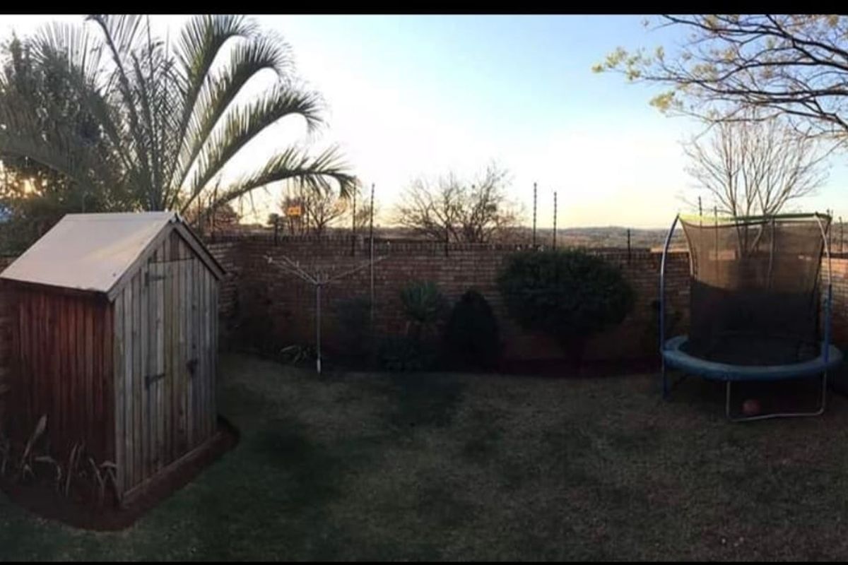 A private rear garden featuring a brick boundary wall with electric fencing, a wooden storage shed, and a rotary clothesline.