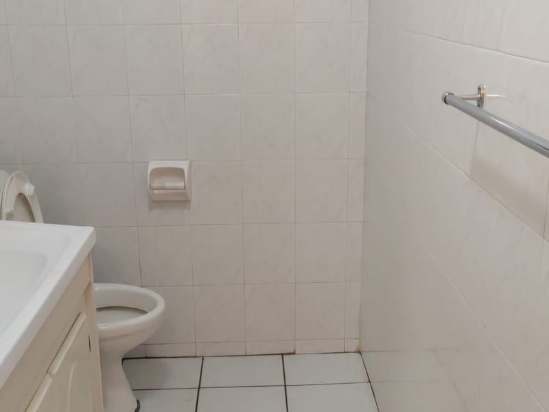 A functional bathroom featuring a vanity cabinet, toilet, and tiled surfaces. The space is ready for modernization to enhance its aesthetic appeal.