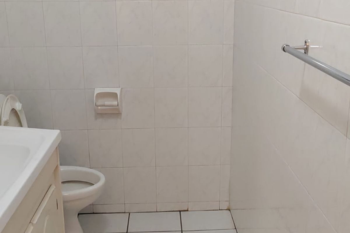 A functional bathroom featuring a vanity cabinet, toilet, and tiled surfaces. The space is ready for modernization to enhance its aesthetic appeal.