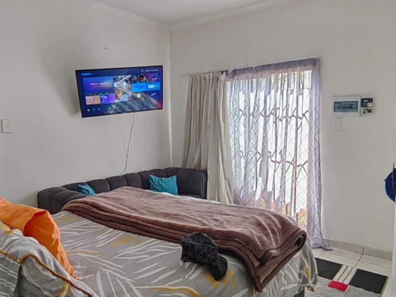 A bedroom featuring tiled flooring and a sliding glass door with a security gate, providing access to the exterior.