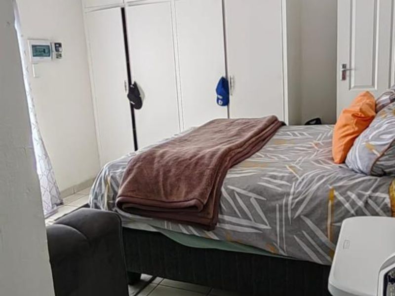 A bedroom featuring built-in cupboards, tiled flooring, and a ceiling-mounted spotlight fixture.
