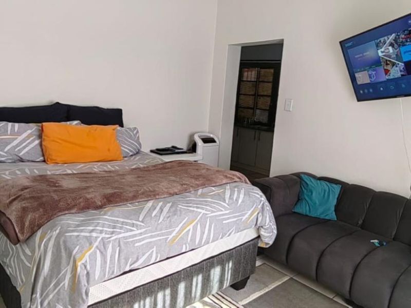 A bedroom featuring tiled flooring, an en-suite bathroom, and a wall-mounted television.
