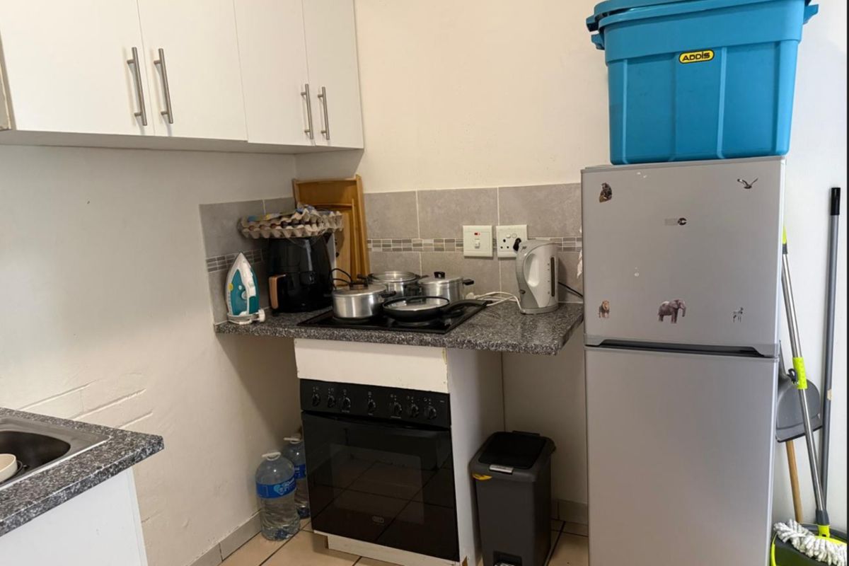 Compact kitchen featuring built-in cabinetry, granite countertops, a ceramic tile backsplash, and a built-in oven with an electric hob.